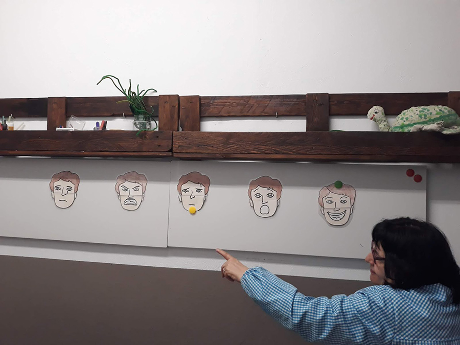 Fotografía de una usuaria señalando su emoción en un dibujo de una cara colgado de la pared