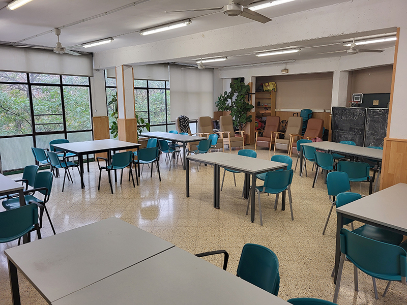 Fotografia de la sala del centre ocupacional amb taules i cadires.